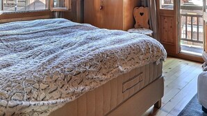 Ein gemütliches Zimmer mit einem großen Bett, Holzmöbeln und Blick durch ein Fenster.