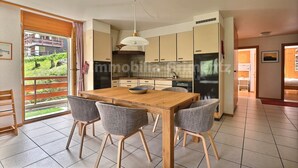 A modern kitchen with a wooden dining table, four chairs, and a hanging light fixture. - Very comfortable flat for 5 people, living room with fireplace, kitchen area with dishwasher, 1 2-be (Grimentz)