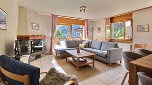 A living room with a stone fireplace, a sofa, a coffee table, and a dining area. - Very comfortable flat for 5 people, living room with fireplace, kitchen area with dishwasher, 1 2-be (Grimentz)