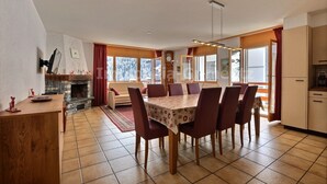 A dining area with a table set for six, a fireplace, and a kitchen area with cabinets and a refrigerator. - Very comfortable flat for 7 people, living room with fireplace, kitchen area with dishwasher, 1 doub (Grimentz)