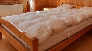 A wooden bed with white bedding in a room with wooden walls and floors. - Very comfortable flat for 7 people, living room with fireplace, kitchen area with dishwasher, 1 doub (Grimentz)