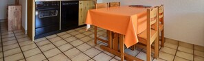 Efficient kitchen with oven and dishwasher, adjacent to a dining area with a wooden table.