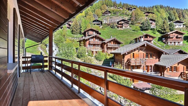 Un pontile in legno con vista sui caratteristici chalet di montagna.