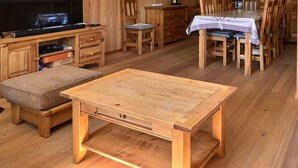 Un soggiorno con pavimento in legno, una TV, un tavolo di legno e un divano.