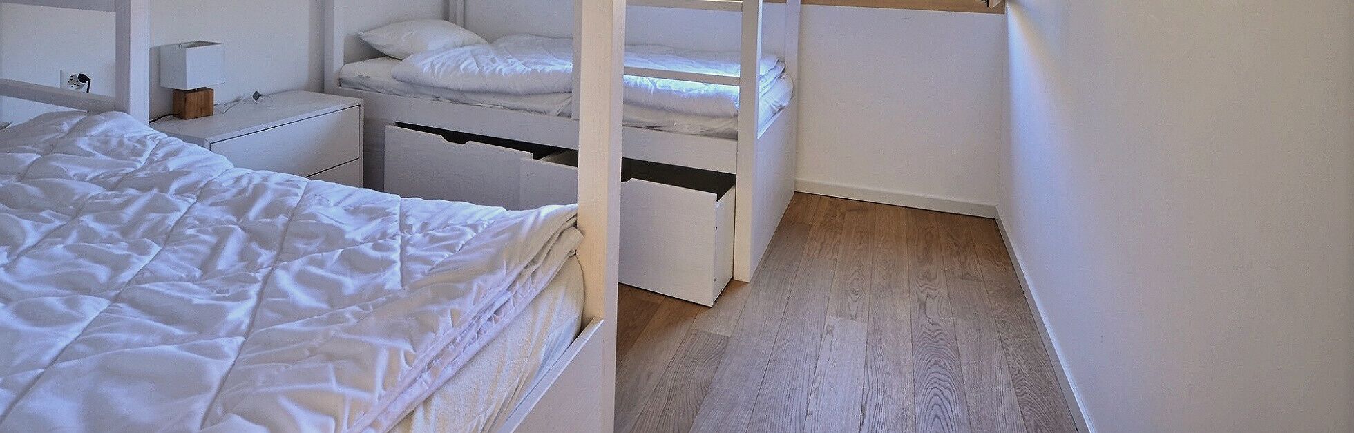 Une chambre à coucher comprenant un lit, une table de chevet, une commode et un lit superposé.