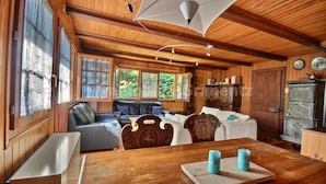 L’intérieur d’un chalet en bois, avec une table à manger, des chaises, un canapé et un luminaire au plafond.