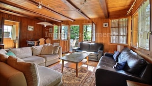 L’intérieur chaleureux d’un chalet avec des murs en bois, une grande fenêtre et une cheminée.