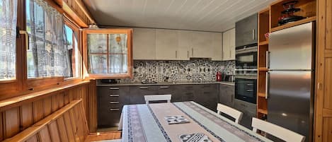 Eine Küche mit Holzschränken, einem Edelstahlkühlschrank und einer gefliesten Spritzschutzwand.
