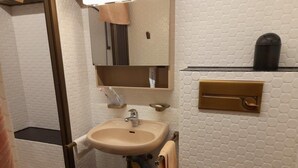 A bathroom with a white hexagonal tile wall, a beige sink, a mirror, and a towel rack.