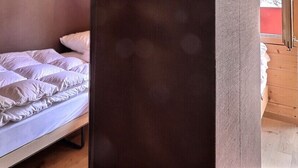 A bed with white bedding, a wooden headboard, and a view of a wooden deck outside.