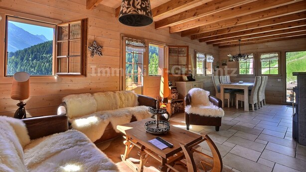 L’intérieur d’un chalet en bois comprend un coin repas, une cheminée et offre une vue sur les montagnes.