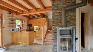 Une cuisine avec des meubles en bois, un mur en pierre et un poêle à bois.