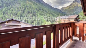 A wooden balcony overlooking a mountainous landscape with dense forests and a valley. - Comfortable flat on 2 levels for 4 to 6 people, living room with 1 double divan bed, kitchen area wi (Grimentz)