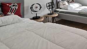 A modern bedroom with a large bed, a smaller bed, a bedside table with a lamp, and a red pillow. - Comfortable flat on 2 levels for 4 to 6 people, living room with 1 double divan bed, kitchen area wi (Grimentz)