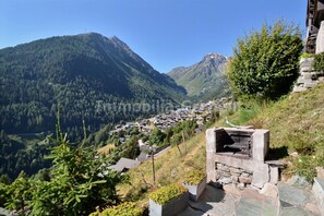 A mountainous village with stone-built houses, a stone barbecue area, and a clear view of the valley below. - Comfortable flat for 4 to 6 people, living room with 1 double divan bed, kitchen area with dishwashe (Grimentz)