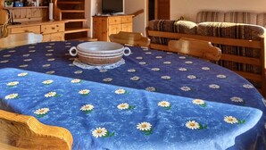 A round wooden table with a blue floral tablecloth and a central white plate. - Comfortable chalet on 2 levels for 7 to 8 people, living room, kitchen area with dishwasher, 1 doubl (Grimentz)
