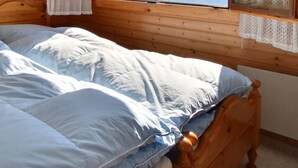 A wooden bed with a blue and white duvet in a room with wooden walls and a wooden nightstand. - Comfortable chalet on 2 levels for 7 to 8 people, living room, kitchen area with dishwasher, 1 doubl (Grimentz)