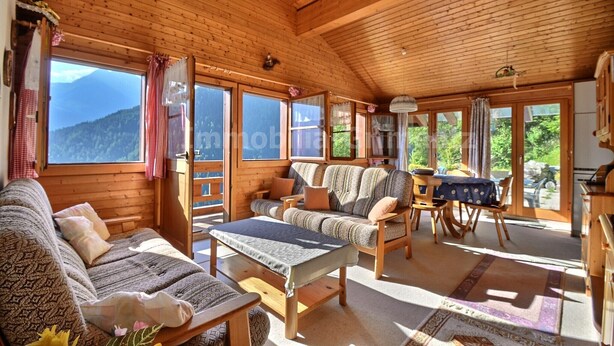 A cozy cabin with wooden walls and ceilings, a sofa, a dining table, and large windows offering mountain views. - Comfortable chalet on 2 levels for 7 to 8 people, living room, kitchen area with dishwasher, 1 doubl (Grimentz)