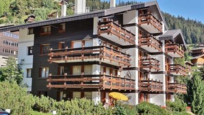 A multi-story hotel with wooden balconies and a mountain backdrop. - Comfortable flat for 4 people, living room, kitchen area, 1 2-bedroom, sleeping corner with 1 bunk b (Grimentz)