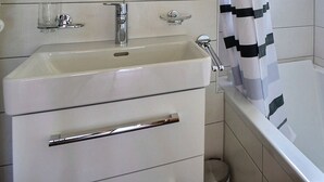 A bathroom with a white sink, a bathtub, and a shower. - Comfortable flat for 6 people, living room with fireplace, kitchen area with dishwasher, 1 2-bedroom (Grimentz)
