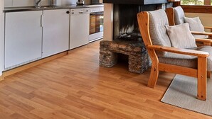 A cozy living room with a fireplace, wooden furniture, and a kitchen area with white cabinets. - Comfortable flat for 6 people, living room with fireplace, kitchen area with dishwasher, 1 2-bedroom (Grimentz)