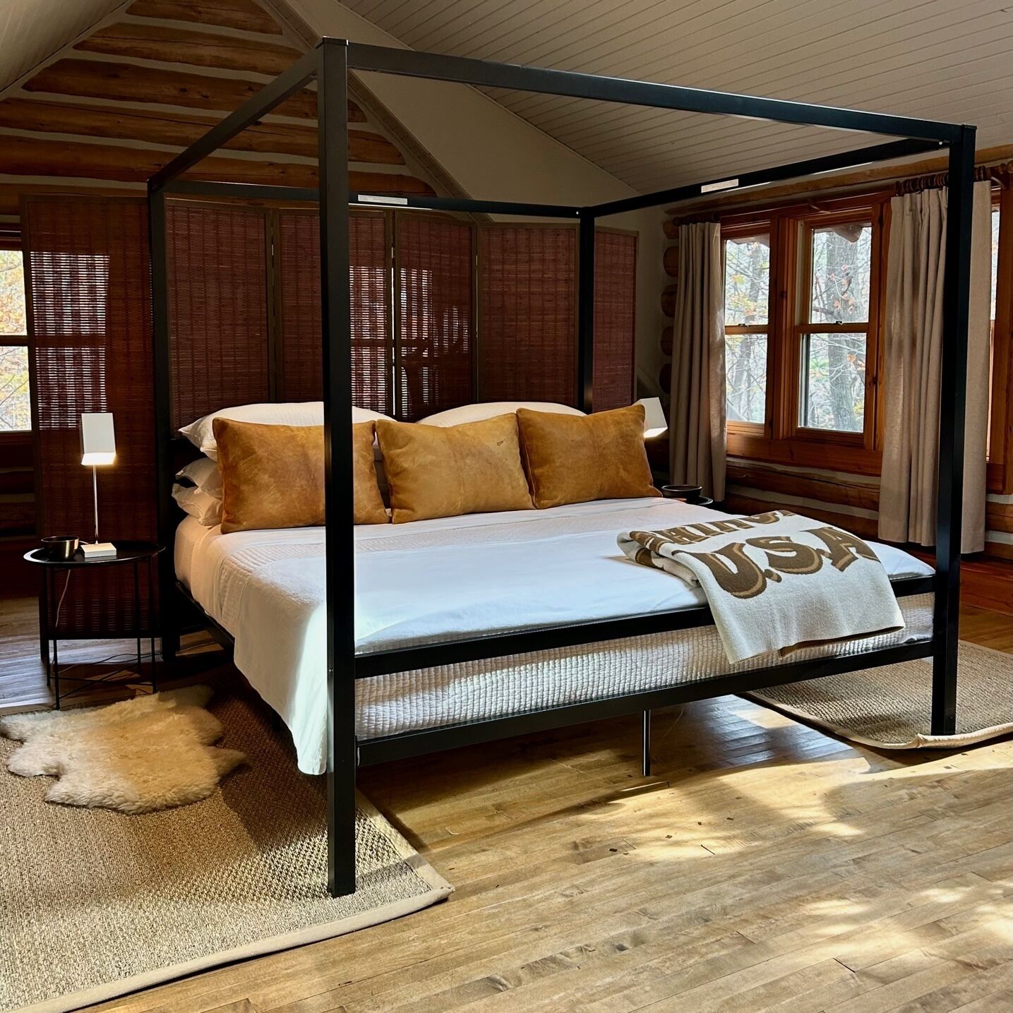 A four-poster bed with a white bedspread and a USA-themed throw blanket.