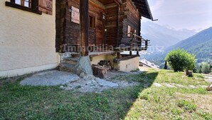 A rustic wooden cabin with a stone foundation, a wooden porch, and a view of a mountainous landscape. - Comfortable traditional chalet on 2 levels for 7 to 8 people, living room, separated kitchen with di (Grimentz)