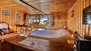 L’intérieur d’un chalet en bois comprend un grand lit, une table à manger et un coin cuisine.