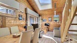 Uma cabana acolhedora com área de jantar, TV e quarto mezanino com claraboia.
