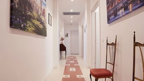 A hallway with a patterned carpet, two wooden chairs, and two large paintings on the walls. - FLAMINIA STREET APARTMENT (Roma)