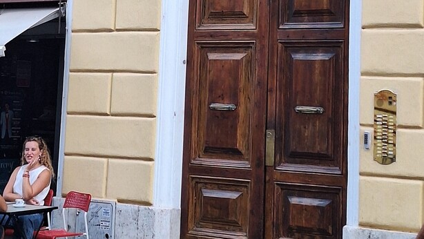 A yellow building with a large wooden door and two windows with shutters. - FLAMINIA STREET APARTMENT (Roma)
