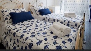 A bedroom with two beds, each with a floral-patterned bedspread, a white metal headboard, and a blue pillow. - FLAMINIA STREET APARTMENT (Roma)