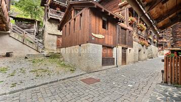 Eine enge Kopfsteinpflasterstraße, gesäumt von traditionellen Holzbauten mit Balkonen und Blumenkästen.