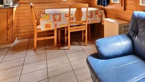 A cozy cabin interior with a blue leather sofa, wooden dining table, and chairs.