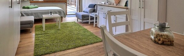 Ein kompakter Wohnraum mit Bett, einer kleinen Essecke und einer Küchenzeile.