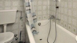 A bathroom with a bathtub, a sink, and a toilet. - Comfortable studio for 2 people, living room with 1 double bed, kitchen area with dishwasher, bath-W (Grimentz)