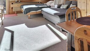 Et træbord med to servietter, en sofa og en seng i et rum med trævægge og en radiator.