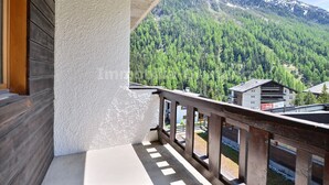 Un balcon offrant une vue sur une chaîne de montagnes boisées et un bâtiment orné d’une enseigne Coca-Cola.