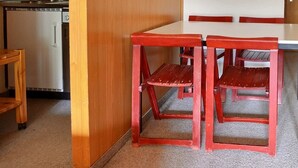 Une petite cuisine avec un réfrigérateur blanc, une table en bois et deux chaises rouges.