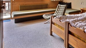 Une chambre à coucher avec un lit en bois, un banc, une chaise et une table de chevet avec une lampe.