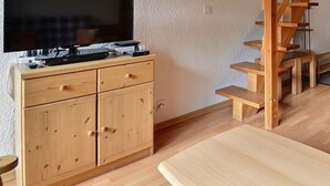 Ett modernt, minimalistiskt rum med ett skrivbord i trä, en tv och en trappa.