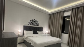 A modern bedroom with a large bed, bedside lamps, a decorative wall piece, and a window with curtains. - JRE Cozy Home Near All Services 20 (Amman)