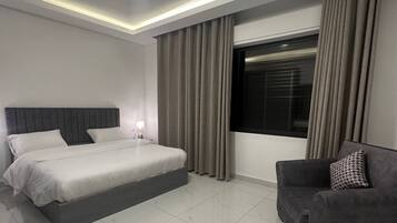 A modern bedroom with a bed, a sofa, a window with curtains, and a ceiling light.