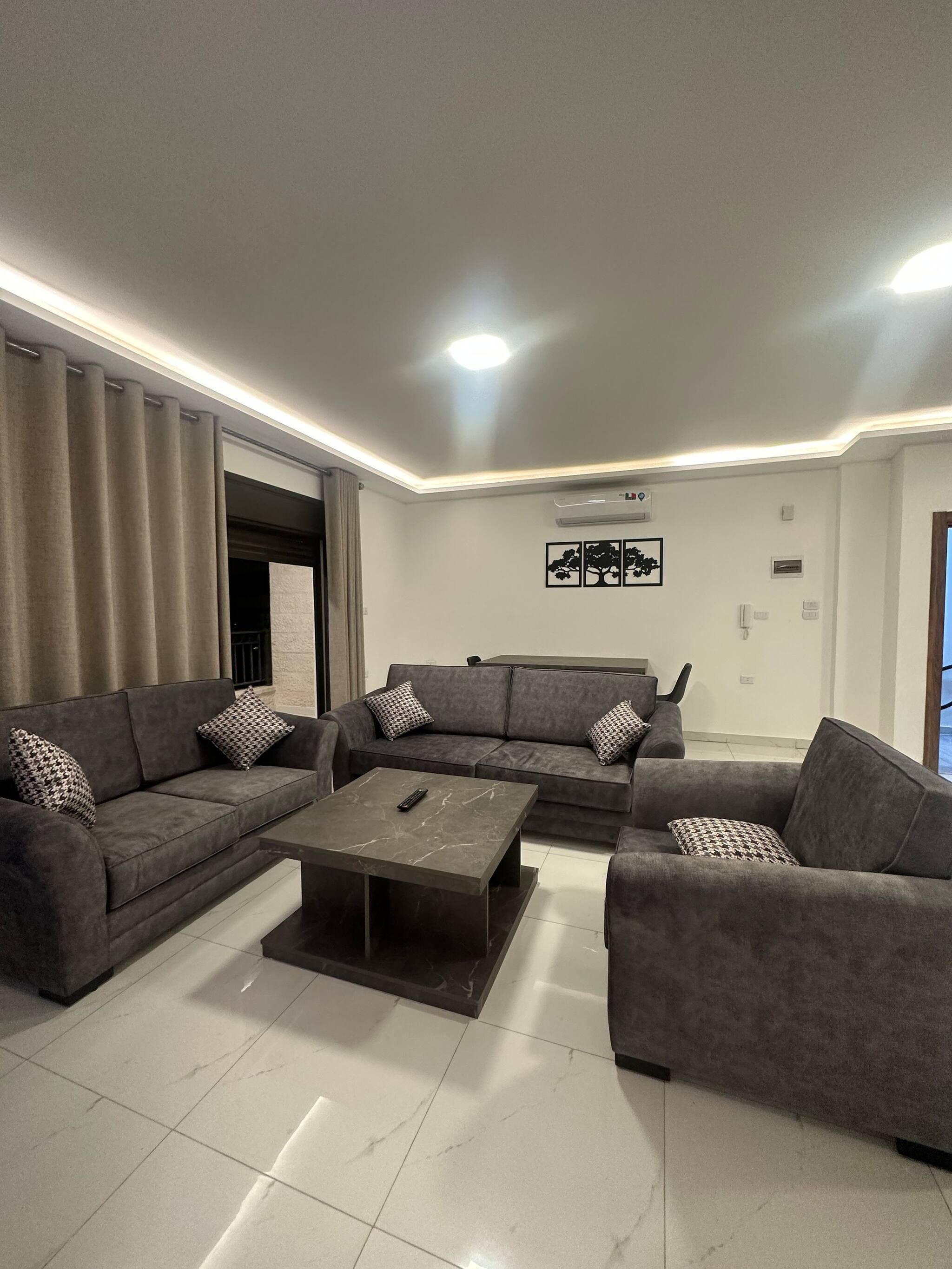 A modern living room with grey sofas, a marble coffee table, and a ceiling light.