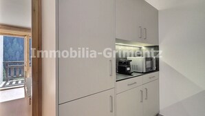 A modern kitchen with built-in appliances, a balcony view, and a minimalist design.