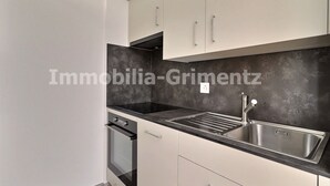 A modern kitchen with a stainless steel sink, a black countertop, and white cabinets.