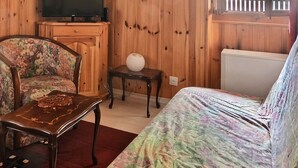 Ein gemütliches Zimmer mit Holzwänden, einem floralen Sofa, einem Holztisch und einem Fernseher.