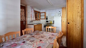 Eine kleine Küche mit Esstisch, Holzstühlen und einer Holztür.