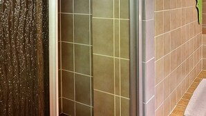 Une salle de bain avec une douche, un lavabo et un banc en bois.