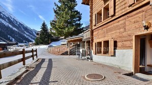 A wooden building with a covered outdoor seating area and a paved walkway. - Comfortable studio for 2 people, living room with 2 beds, kitchen area with dishwasher, shower-WC, s (Grimentz)